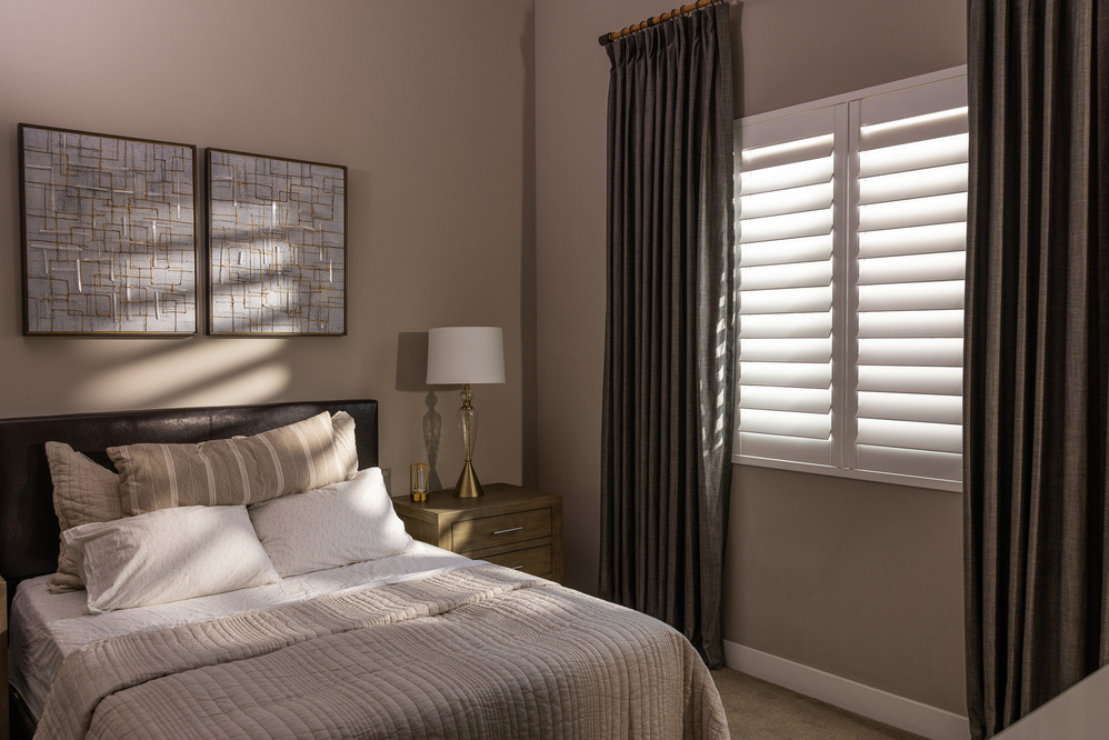 White plantation shutters providing a solid insulating barrier over a bedroom window
