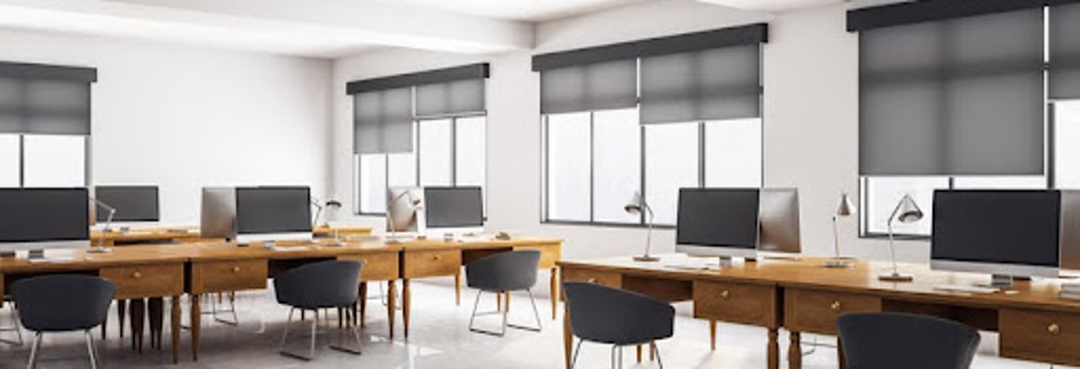 Solar roller shades reduce glare in a modern open office with multiple computer workstations. | Gotcha Covered