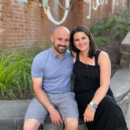 photo of Hailey and her husband sitting in front of a brick wall