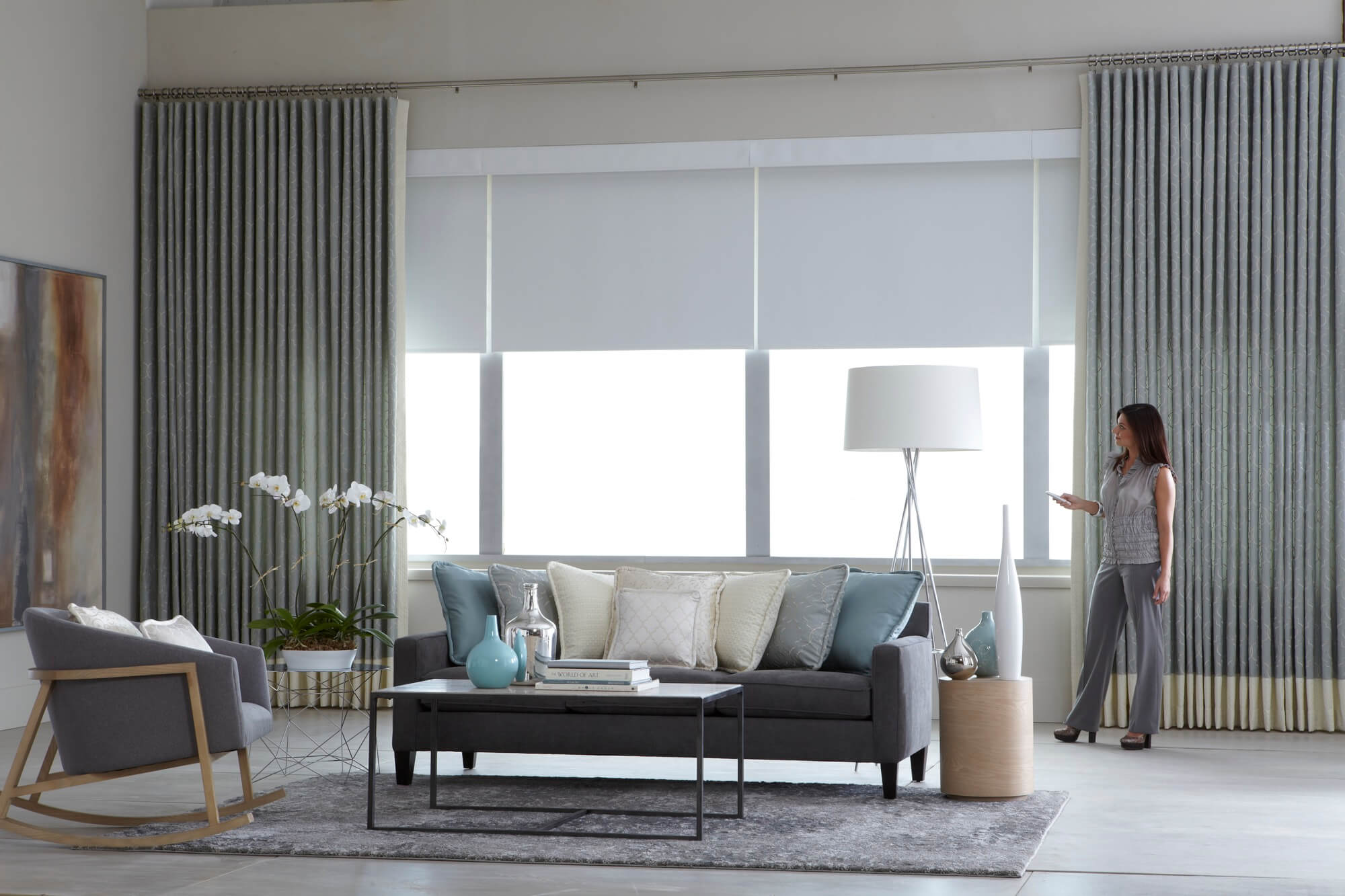 Grey motorized window shades in a high ceiling living room