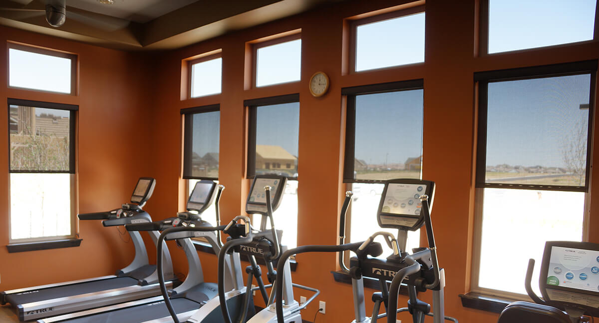 commercial solar shades halfway drawn in fitness room